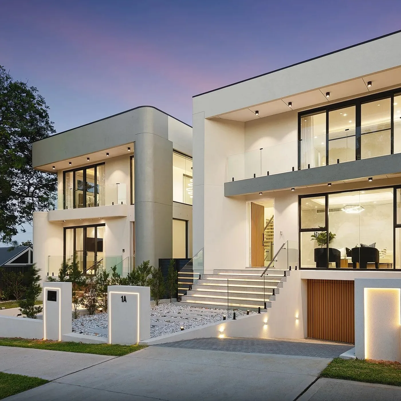 Two storey home at twilight with tall black aluminium windows and glass balustrade - AGM Windows & Doors, Sydney