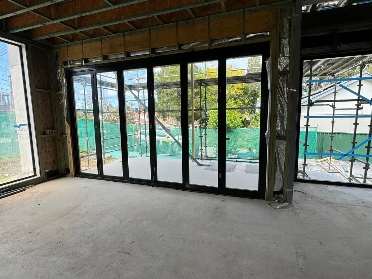 Six panel black aluminium bi-fold doors installed in a new home under construction - AGM Windows & Doors, Sydney