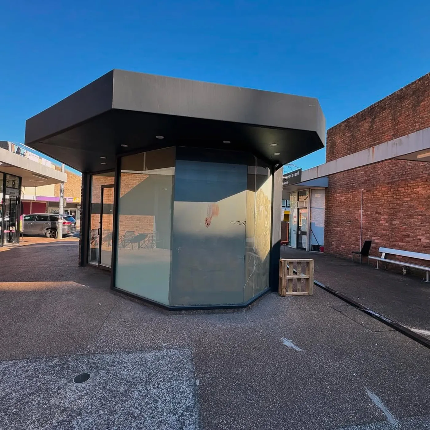Freestanding glass kiosk with black aluminium framing and curved shopfront glazing - AGM Windows & Doors, Sydney